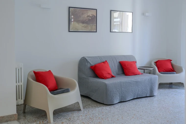 Casa Sanfelice, Roma: il salotto con il divano grigio e i cuscini rossi